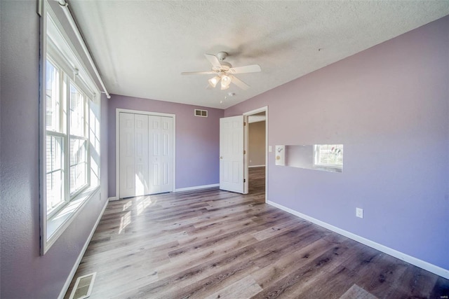 unfurnished bedroom featuring light hardwood / wood-style flooring, a textured ceiling, a closet, and ceiling fan