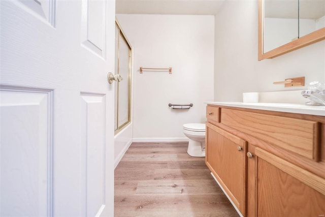 full bathroom featuring shower / bath combination with glass door, vanity, wood-type flooring, and toilet