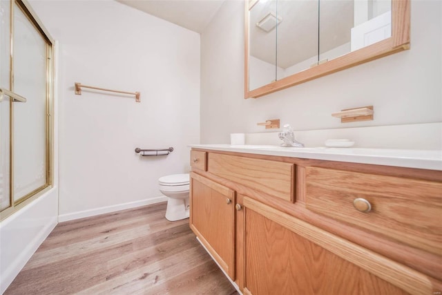 full bathroom featuring vanity, toilet, wood-type flooring, and bath / shower combo with glass door