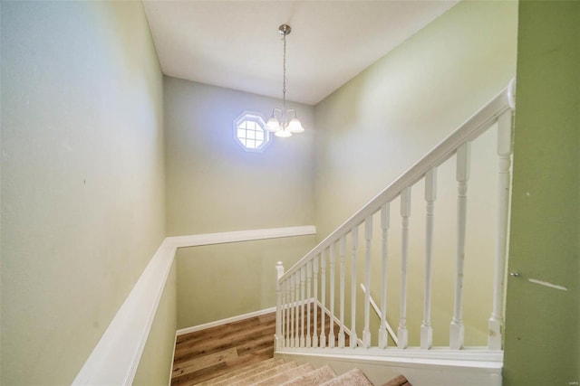 stairway featuring hardwood / wood-style floors and an inviting chandelier