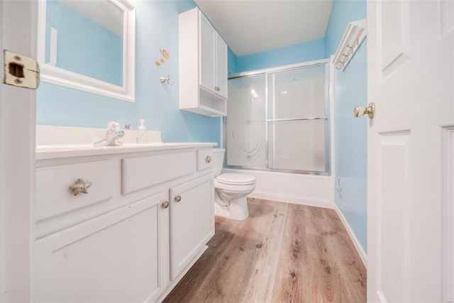 full bathroom featuring vanity, enclosed tub / shower combo, hardwood / wood-style flooring, and toilet