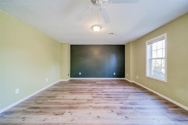 spare room featuring a textured ceiling, light wood-type flooring, and ceiling fan