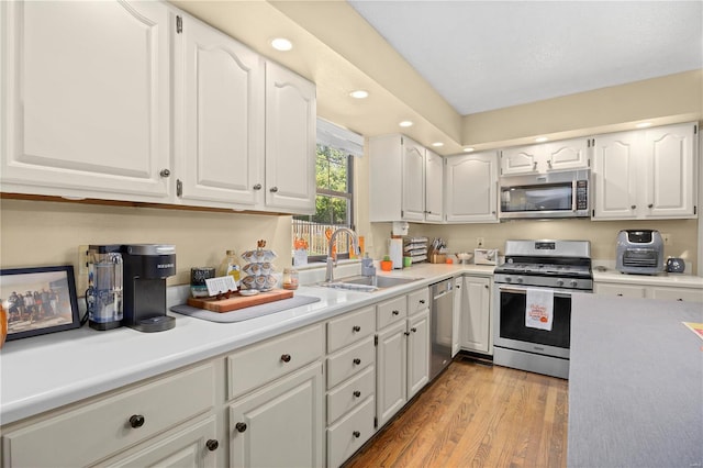 kitchen featuring light hardwood / wood-style floors, appliances with stainless steel finishes, sink, and white cabinetry