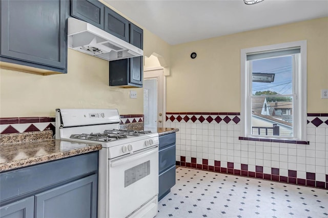 kitchen with white gas range and tile walls