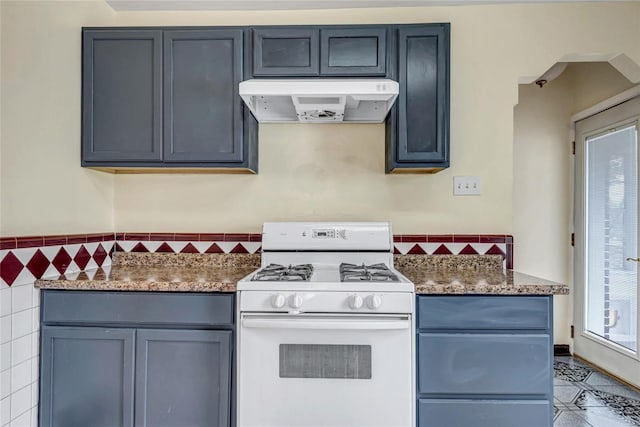 kitchen featuring dark stone countertops, white gas range oven, and a wealth of natural light