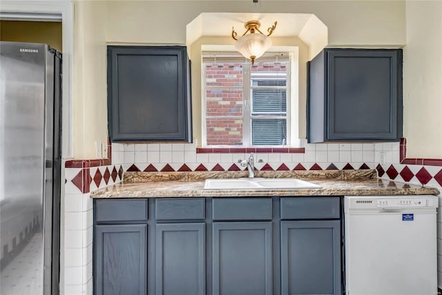 kitchen featuring dishwasher, tasteful backsplash, sink, and stainless steel refrigerator