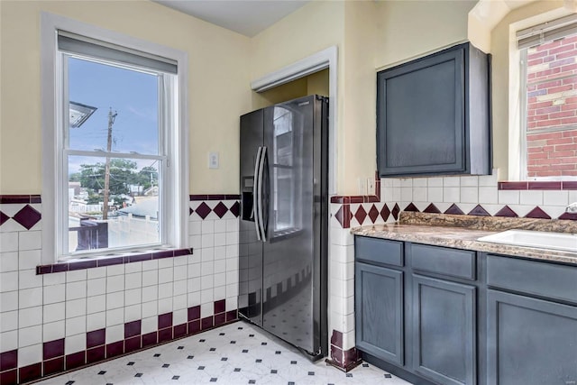 kitchen with gray cabinetry, a healthy amount of sunlight, sink, and black fridge