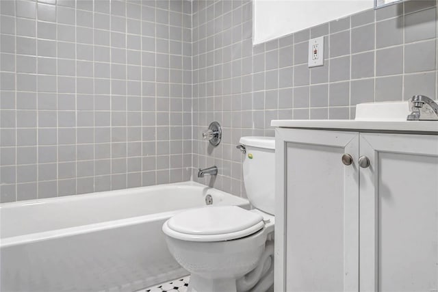 full bathroom with tile walls, toilet, vanity, tiled shower / bath combo, and tile patterned flooring