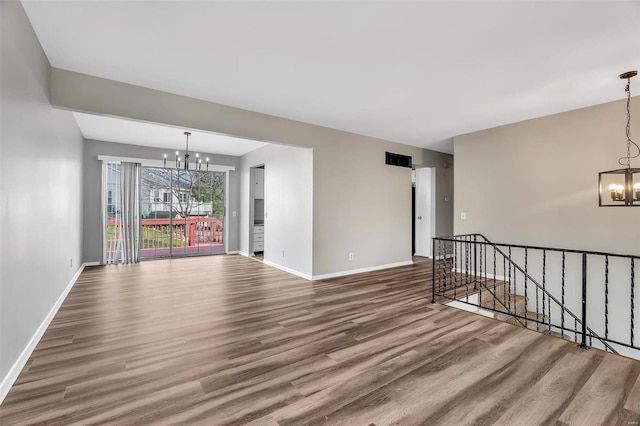 unfurnished room featuring wood-type flooring and an inviting chandelier