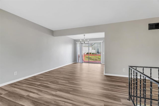 spare room featuring hardwood / wood-style floors and a chandelier