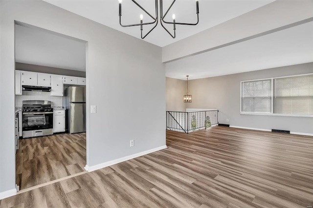 unfurnished living room featuring a notable chandelier and light wood-type flooring