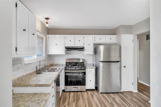 kitchen featuring white cabinetry, backsplash, appliances with stainless steel finishes, and light hardwood / wood-style flooring