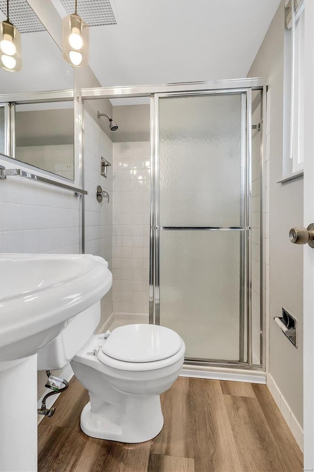 bathroom featuring toilet, wood-type flooring, and a shower with door