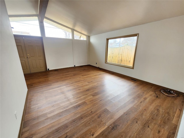 spare room with vaulted ceiling with beams and light wood-type flooring