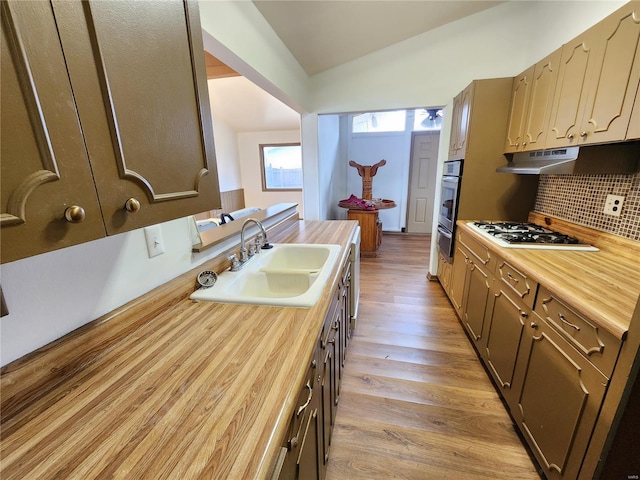 kitchen featuring decorative backsplash, white gas stovetop, sink, light hardwood / wood-style floors, and lofted ceiling