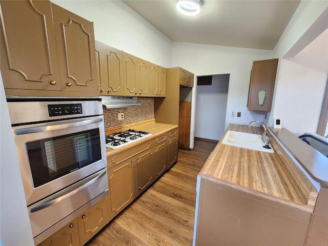 kitchen featuring white gas stovetop, oven, sink, light wood-type flooring, and tasteful backsplash