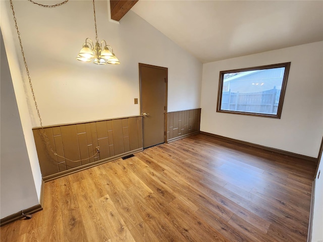 unfurnished room with vaulted ceiling with beams, wood-type flooring, and an inviting chandelier