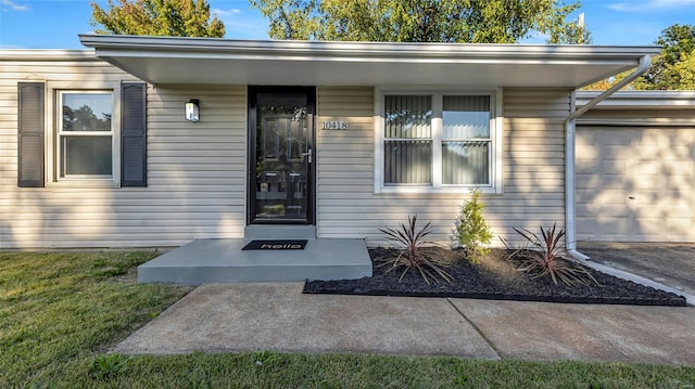 doorway to property with a garage and a lawn