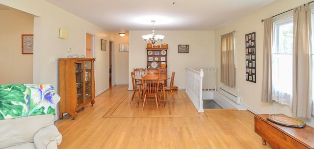 dining room with a notable chandelier, hardwood / wood-style floors, and a baseboard heating unit