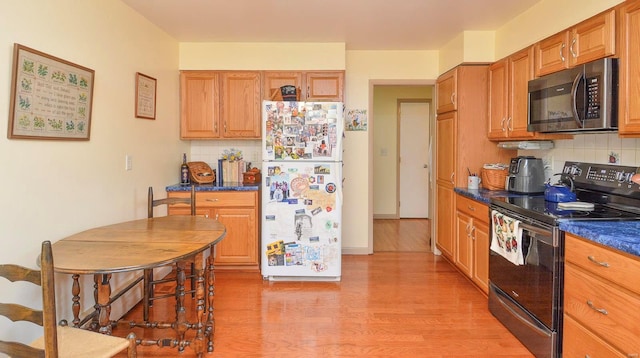 kitchen featuring white refrigerator, light wood-type flooring, tasteful backsplash, and electric range