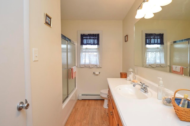 full bathroom featuring enclosed tub / shower combo, vanity, hardwood / wood-style flooring, a baseboard radiator, and toilet