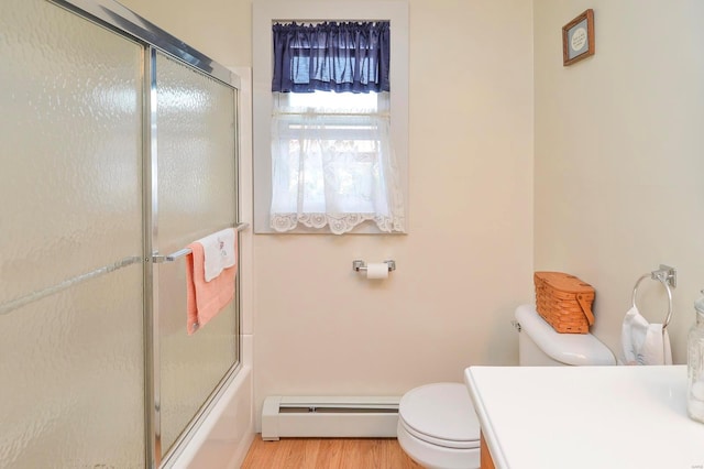 full bathroom featuring vanity, hardwood / wood-style flooring, a baseboard heating unit, toilet, and shower / bath combination with glass door