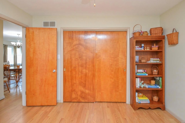 unfurnished bedroom with a closet, an inviting chandelier, and light wood-type flooring