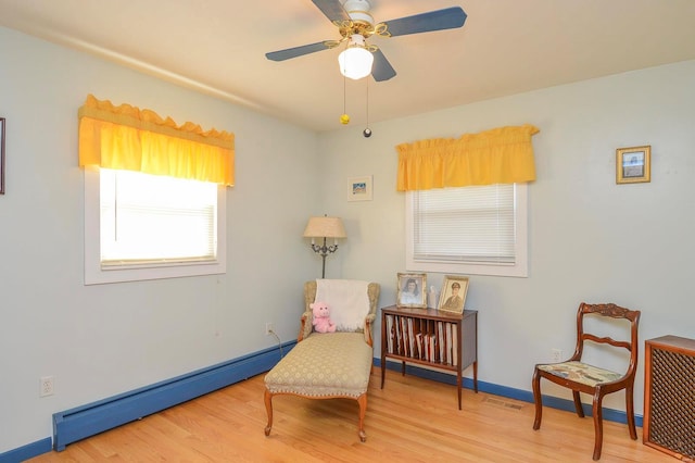 sitting room with wood-type flooring, baseboard heating, and ceiling fan