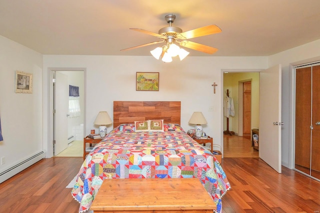 bedroom featuring ceiling fan, a closet, hardwood / wood-style floors, and a baseboard heating unit