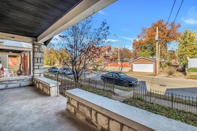 view of patio / terrace featuring covered porch, an outdoor structure, and a garage