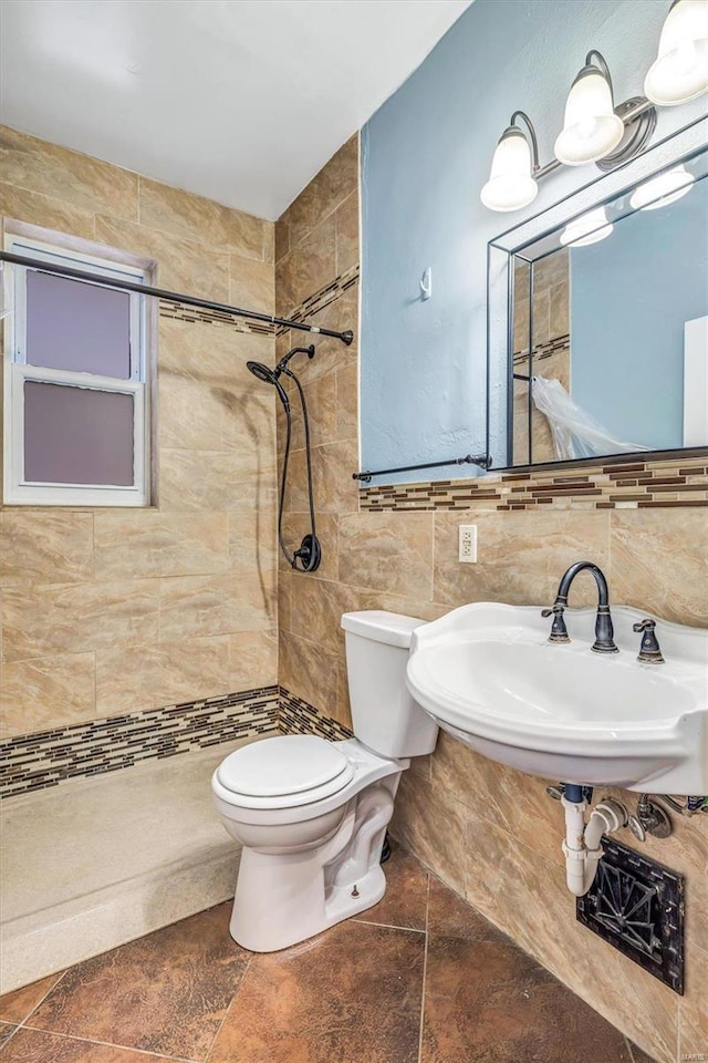 bathroom with tiled shower, tile patterned flooring, tile walls, and toilet