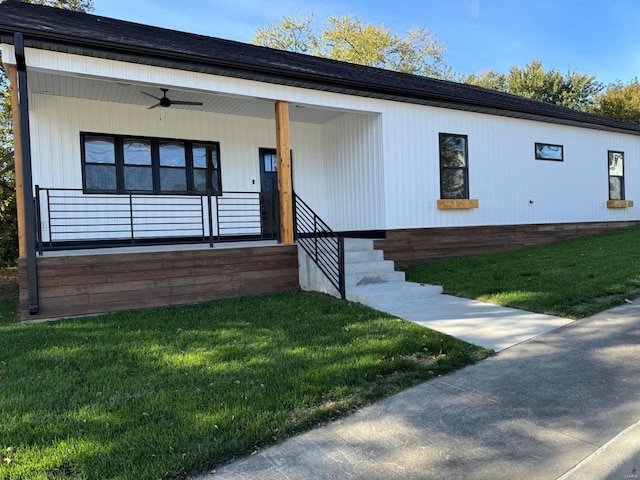 view of front of house with ceiling fan and a front yard