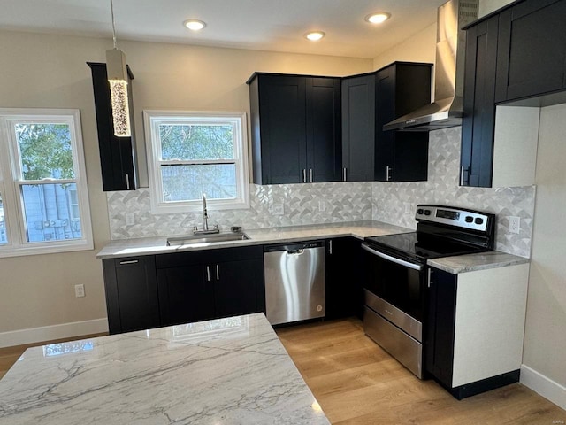 kitchen with wall chimney exhaust hood, plenty of natural light, hanging light fixtures, and stainless steel appliances