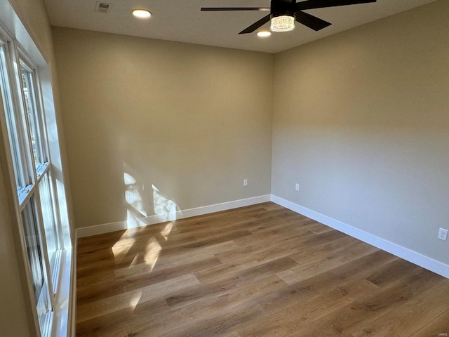 empty room featuring ceiling fan, plenty of natural light, and hardwood / wood-style floors