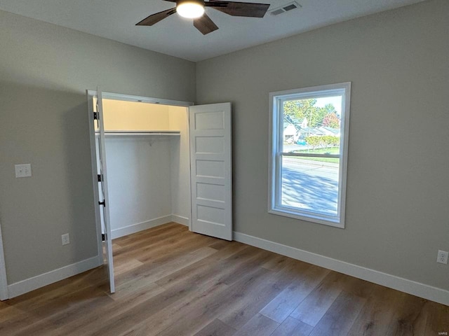 unfurnished bedroom with light wood-type flooring, ceiling fan, and a closet