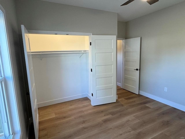 unfurnished bedroom with a closet, hardwood / wood-style flooring, and ceiling fan