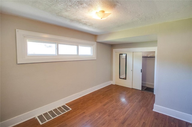 unfurnished room with a textured ceiling, dark wood-type flooring, and a wealth of natural light