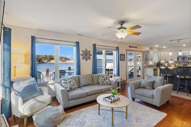 living room featuring a water view, ceiling fan, dark wood-type flooring, and french doors