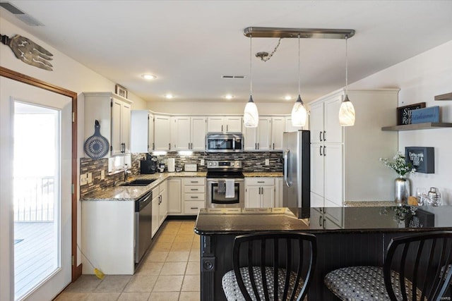 kitchen with appliances with stainless steel finishes, hanging light fixtures, and white cabinetry