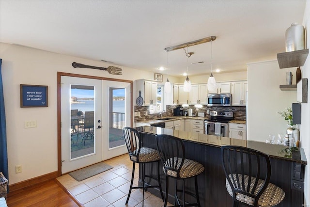 kitchen with french doors, kitchen peninsula, light hardwood / wood-style floors, stainless steel appliances, and white cabinets