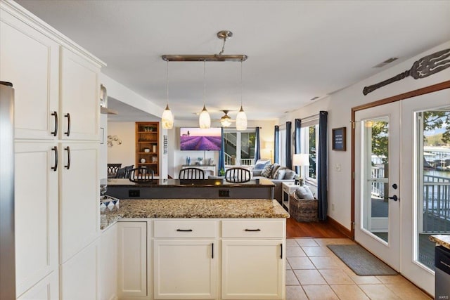 kitchen featuring stone counters, french doors, white cabinetry, light hardwood / wood-style floors, and decorative light fixtures