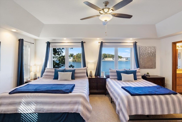 bedroom featuring a water view, multiple windows, light colored carpet, and ceiling fan