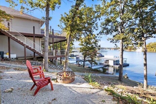 view of yard featuring a deck with water view, a fire pit, and a boat dock