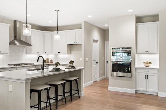 kitchen featuring appliances with stainless steel finishes, white cabinetry, and wall chimney exhaust hood