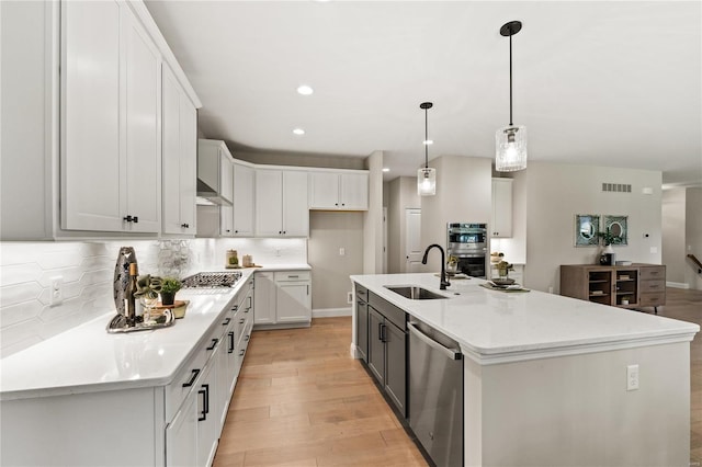 kitchen with stainless steel appliances, white cabinetry, a kitchen island with sink, and sink