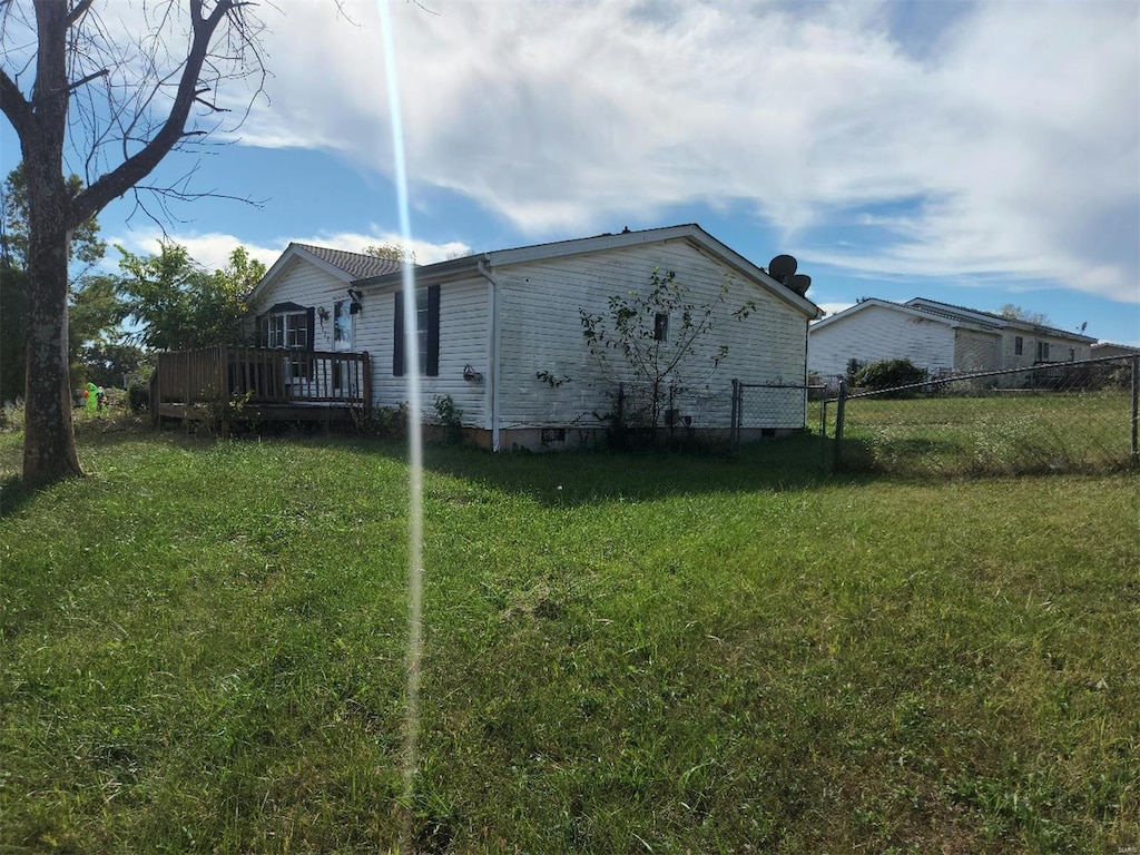 view of side of property with a deck and a lawn