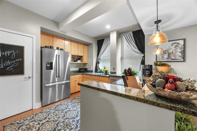 kitchen featuring light brown cabinetry, kitchen peninsula, dark stone counters, pendant lighting, and stainless steel fridge with ice dispenser