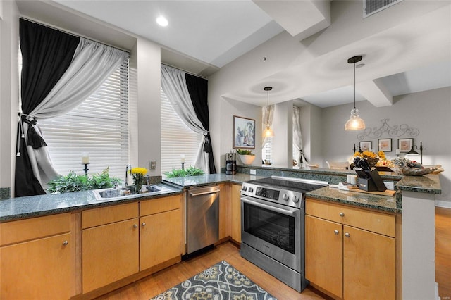 kitchen with sink, kitchen peninsula, stainless steel appliances, dark stone counters, and light hardwood / wood-style flooring