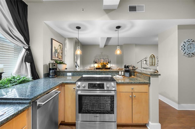 kitchen with hanging light fixtures, kitchen peninsula, dark stone counters, appliances with stainless steel finishes, and dark hardwood / wood-style flooring