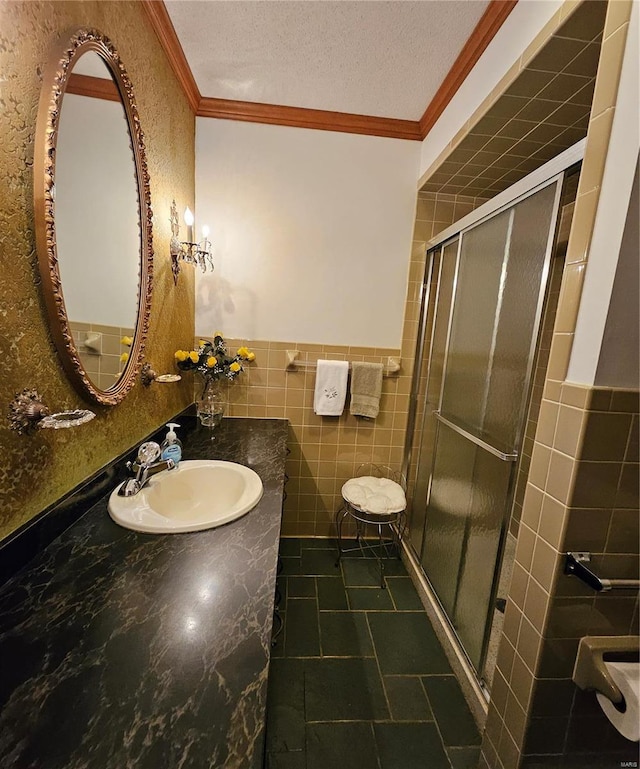 bathroom featuring vanity, tile walls, crown molding, an enclosed shower, and a textured ceiling